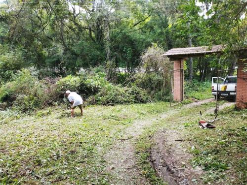 a man standing in a field with a shovel at Cabana de pesca e lazer Represa Usina Mafra sc in Mafra