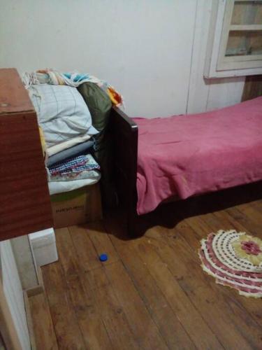 a bedroom with a bed with a pink sheet and a wooden floor at Cabana de pesca e lazer Represa Usina Mafra sc in Mafra