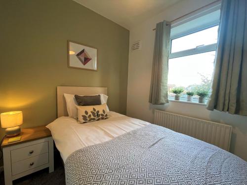 a small bedroom with a bed and a window at Ancaster House - Driveway - Wifi in Lincolnshire