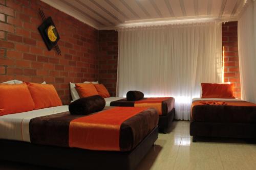 a bedroom with two beds and a brick wall at Hotel Campestre Sueño del Abuelo in Pereira