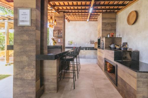 a kitchen with a bar with stools and a fireplace at Casa temporada Condomínio Clube, até 10 pessoas. in Caldas Novas