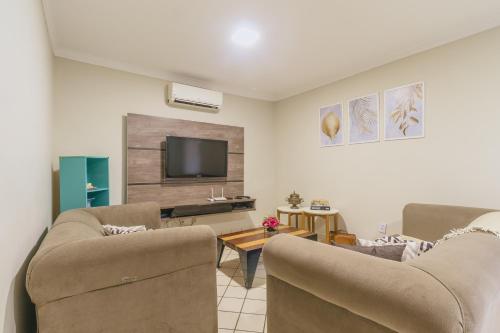 a living room with two chairs and a flat screen tv at Casa temporada Condomínio Clube, até 10 pessoas. in Caldas Novas