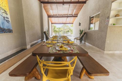 a long dining room with a long table with yellow chairs at Casa temporada Condomínio Clube, até 10 pessoas. in Caldas Novas