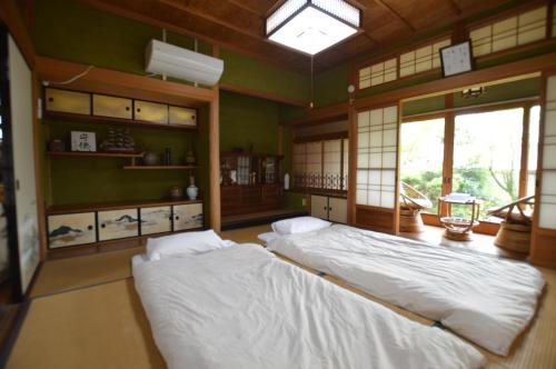 Duas camas num quarto com paredes verdes e janelas em Guest House Ilonggo em Tsu