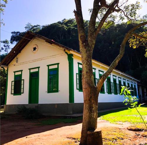 una casa con ventanas con persianas verdes y un árbol en Fazenda inteira e centenária para seu grupo, en Bom Jardim
