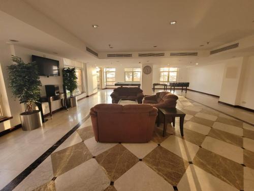 شقة اللوتس  في King Abdullah Economic City: غرفة معيشة كبيرة مع أرائك وأرضية لوح شوكولاتة.