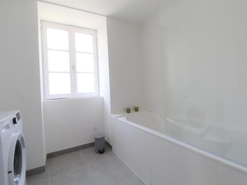 y baño blanco con bañera y lavadora. en Gîte Bouchemaine, 3 pièces, 4 personnes - FR-1-622-15 en Bouchemaine