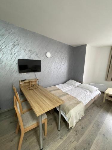 1 dormitorio con 1 cama y escritorio con TV en Apartments Konaci Kopaonik, en Kopaonik