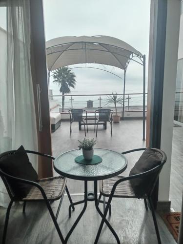 a patio with a table and chairs and an umbrella at Hermosos Dptos Sunset Point Huanchaco in Huanchaco