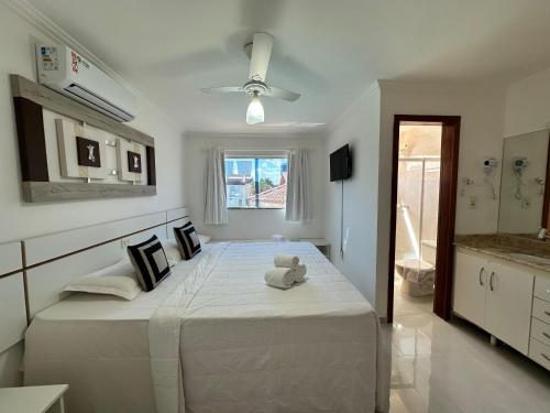 ein weißes Schlafzimmer mit einem Teddybär auf einem Bett in der Unterkunft Flat em Condomínio Mont Sião in Porto Seguro