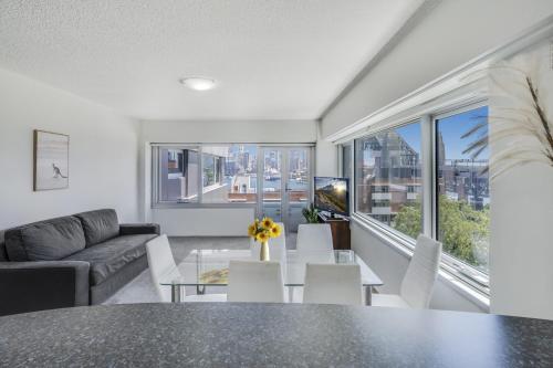 een woonkamer met een tafel en stoelen en een bank bij Sydney Harbour View Apartments in Sydney