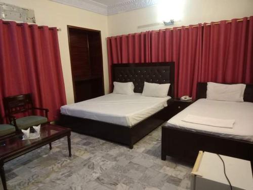 een slaapkamer met 2 bedden en rode gordijnen bij Karachi Airport Hotels in Karachi