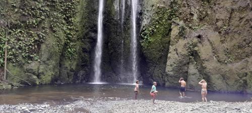 a group of people standing in the water near a waterfall at Yasur View Bungalow and Tree House in White Sands