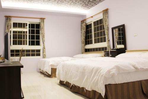 two beds in a white room with windows at Lefu B&B in Dongshan