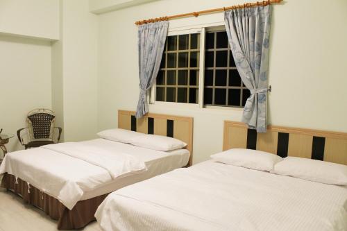 two beds in a room with a window at Lefu B&B in Dongshan