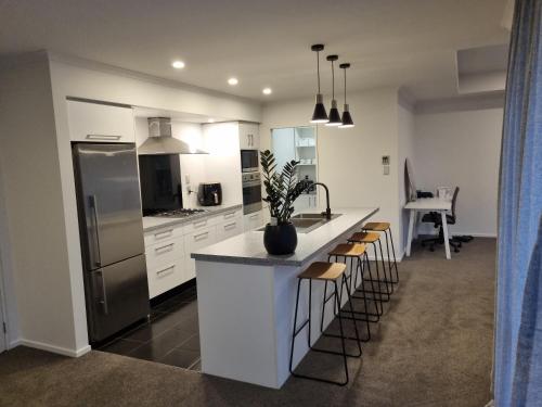 a kitchen with white cabinets and a counter with stools at Home away from home in Rolleston in Rolleston