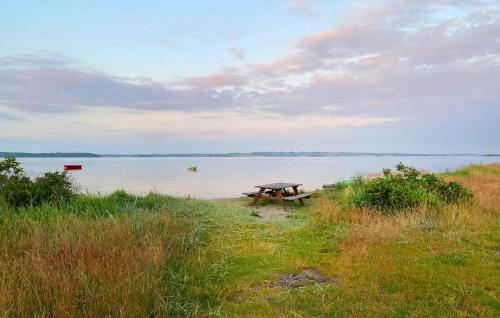a picnic table sitting on the shore of a lake at Holiday Home Havhusevej Hornslet Xii in Hornslet