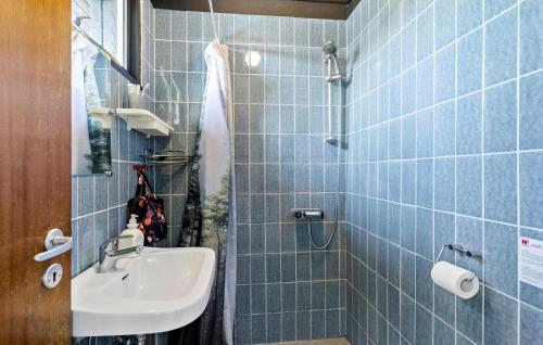 a blue tiled bathroom with a sink and a shower at Amazing Home In Svendborg With Kitchen in Vemmenæs