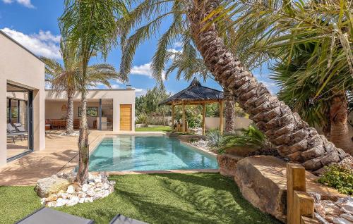 une piscine dans une cour avec des palmiers dans l'établissement Ruben, à Puimisson