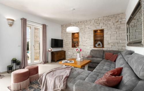 un salon avec un canapé gris et un mur de briques dans l'établissement Villa Bincila Labinci, à Poreč