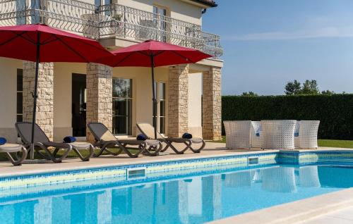 une piscine avec chaises longues et parasols à côté d'une maison dans l'établissement Villa Bincila Labinci, à Poreč
