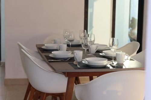a wooden table with white plates and wine glasses at Villas Miland - San Benito Beach in San Benito