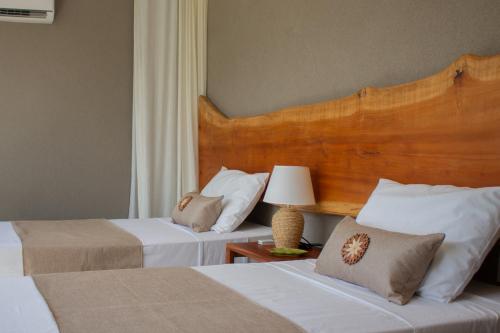a bedroom with two beds and a wooden headboard at Casa na Praia em Milagres - Casa Rudá in São Miguel dos Milagres