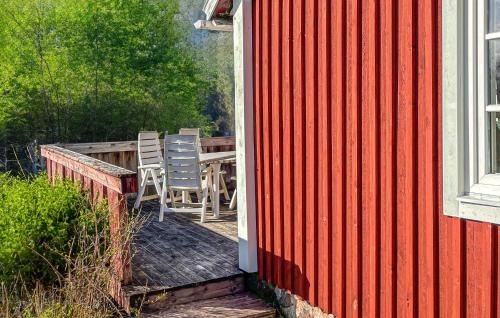 a red house with a deck with chairs and a table at 2 Bedroom Gorgeous Home In Hamneda in Annerstad