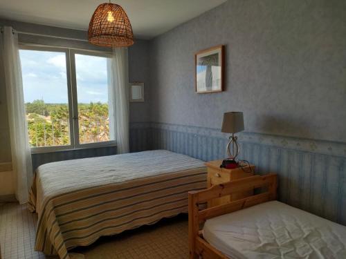 une chambre avec deux lits et une fenêtre dans l'établissement Appartement 1 chambre proche plage et commerces, garage privé, animaux admis - FR-1-323-411, à Saint-Jean-de-Monts
