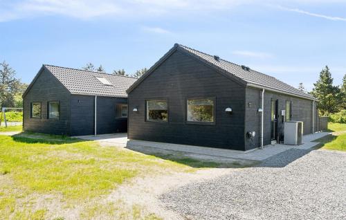 a black house sitting on top of a field at Gorgeous Home In Blåvand With Sauna in Blåvand