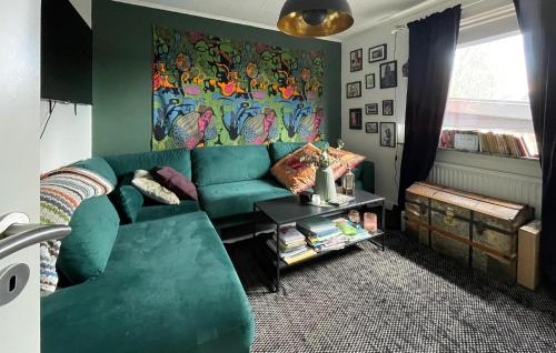a living room with a green couch and a painting at Awesome Home In Rydboholm With Sauna in Rydboholm