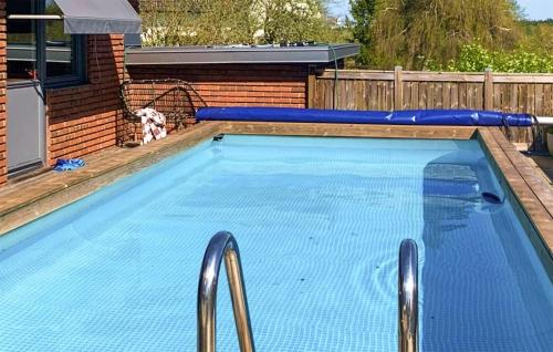 a large swimming pool with blue water in a backyard at Awesome Home In Rydboholm With Sauna in Rydboholm