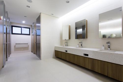 a bathroom with two sinks and two mirrors at Hotel Logenir in Gimcheon