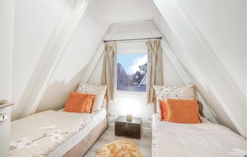 two beds in a attic room with a window at Stunning Home In Friedrichskoog in Friedrichskoog