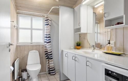 a white bathroom with a toilet and a sink at Four-Bedroom Holiday Home In Orsted in Ørsted