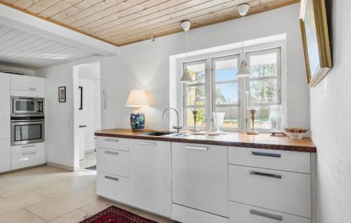 a kitchen with white cabinets and a sink and a window at Cozy Home In Gilleleje in Gilleleje
