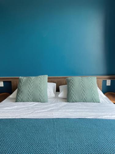 a bed with two pillows and a blue wall at El Pino House in Khu Chi Lăng