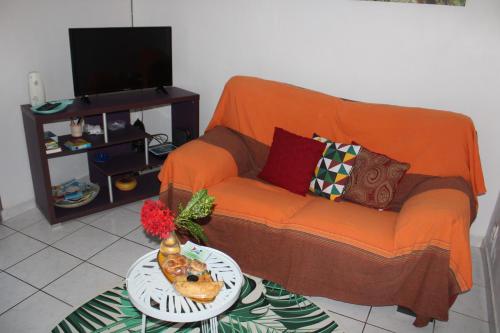 um sofá laranja numa sala de estar com uma mesa em Le Colibri et le Frangipanier em La Trinité