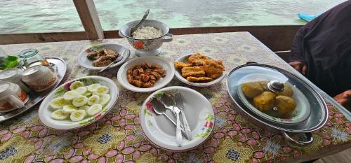 einen Tisch mit Teller mit Lebensmitteln auf einem Tisch in der Unterkunft KIA HOMESTAY in Banggai