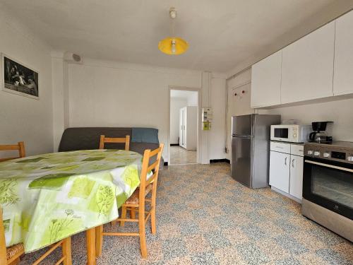 une cuisine avec une table et une cuisine avec un micro-ondes dans l'établissement Appartement cosy avec balcon, plage à 150m, parking, animaux sur demande - La Faute-sur-Mer - FR-1-476-220, à La Faute-sur-Mer