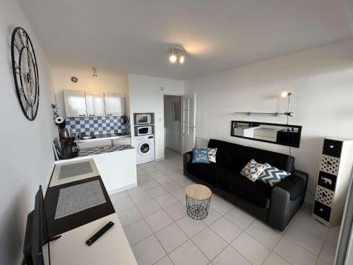 un salon avec un canapé noir et une cuisine dans l'établissement Studio confortable avec balcon et lave-linge à Saint-Jean-de-Monts - FR-1-224C-302, à Saint-Jean-de-Monts