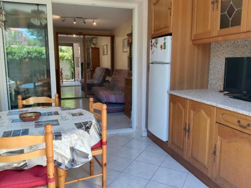 une cuisine et une salle à manger avec une table et un réfrigérateur dans l'établissement Studio climatisé avec Jardinet, Piscine et Parking à 500m de la Plage - FR-1-776-96, à Argelès-sur-Mer