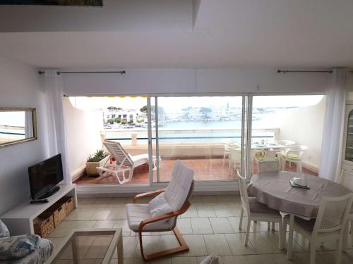 un salon avec une table et des chaises et un balcon dans l'établissement Marina 2 pièces avec terrasse et parking, animaux admis, proche plage - FR-1-307-260, au Grau-du-Roi