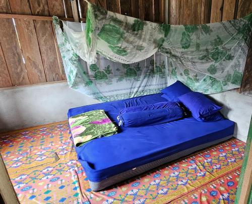 Bett mit blauen Kissen auf einem Zimmer in der Unterkunft KIA HOMESTAY in Banggai