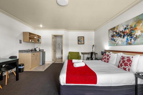 a bedroom with a large bed and a kitchen at Tuscany Villas Whakatane in Whakatane