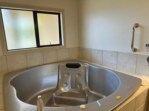 a large tub in a bathroom with a window at Tuscany Villas Whakatane in Whakatane