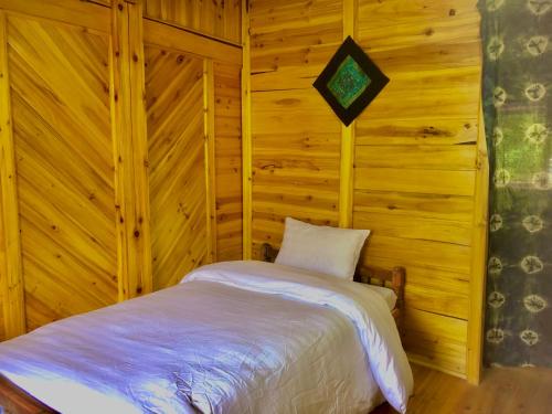 ein Schlafzimmer mit einem Bett in einer Holzwand in der Unterkunft Lysa House in Lào Cai