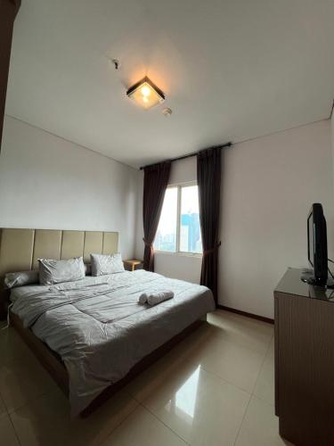 1 dormitorio con 1 cama y TV en Comfy & Modern 1BR At Central, en Yakarta