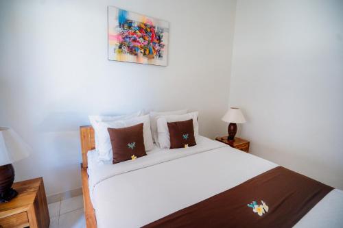 a bedroom with a white bed with two night stands at Kayuma House Canggu in Canggu