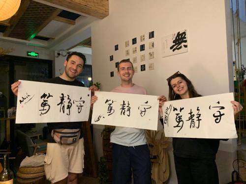 a group of three people holding up signs with chinese characters at Zhangjiajie One Art Guesthouse in Zhangjiajie